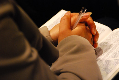 Se observan las manos de una persona orando, con las manos unidas, sobre la Biblia.