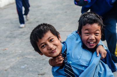 Dos niños posan frente a la cámara, y uno sostiene al otro, en una expresión de amistad.