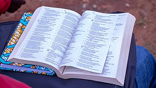 Una biblia abierta, en salmos 36, sobre una maleta, en el regazo de una persona.